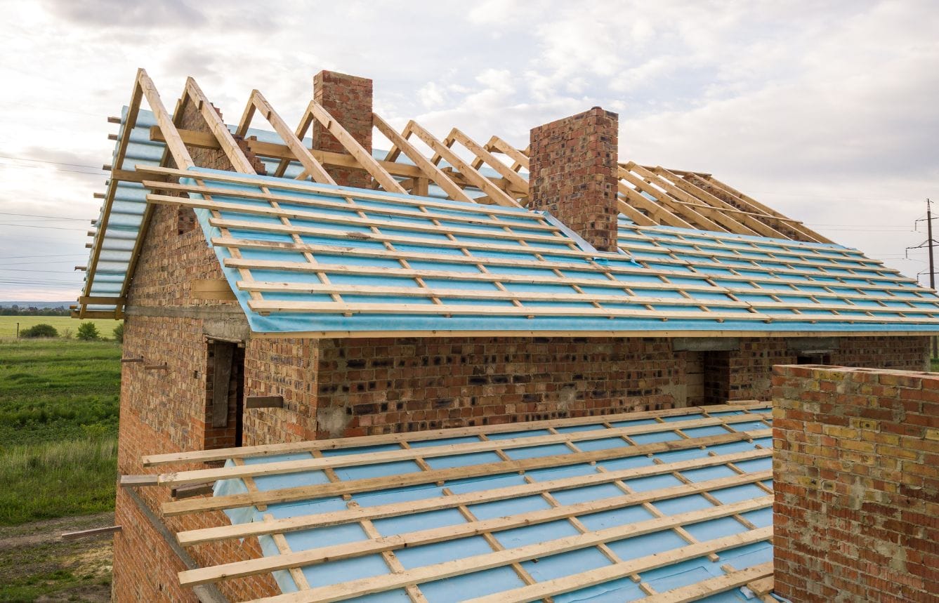 Brick house under construction with wooden roof frame.